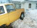 1966 Ford Bronco - A yellow 1966 Ford Bronco is partially buried in snowdrifts next to a house.