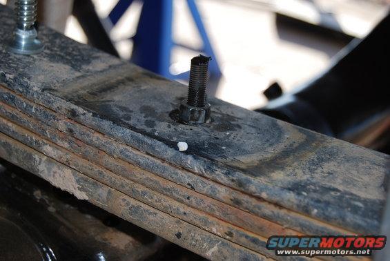 Leaf spring assembly with a bolt and nut, showing rust and wear