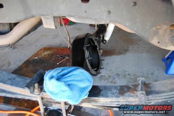 Undercarriage of a vehicle with leaf springs, a shock absorber, and a brake rotor assembly. A blue towel is on the leaf spring