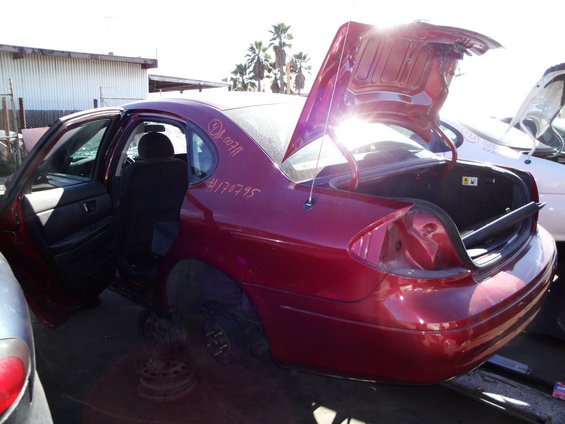 Red sedan with open doors and trunk, missing wheels. Red handwritten numbers on the rear quarter panel