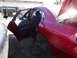 2003 Ford Taurus - Rear door panel of a red 2003 Ford Taurus, showing interior details and missing wheels.