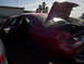 2003 Ford Taurus - A red sedan sits in a junkyard with its doors and trunk open, showing some handwritten markings on its body.