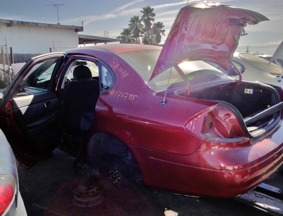 Red 2003 Ford Taurus sedan with open doors and trunk, showing interior and rear quarter panel damage