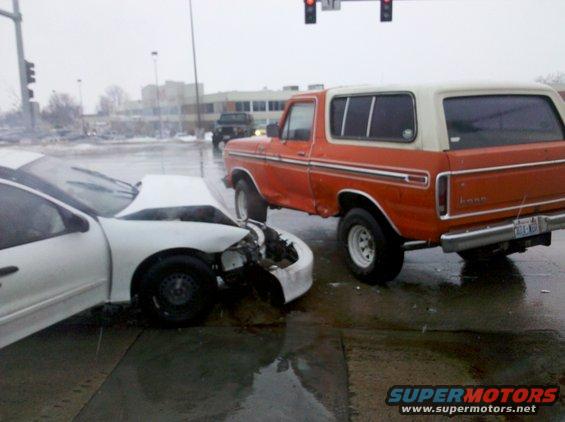 Orange and white 1979 Ford Bronco rear 3/4 view after collision with a white car
