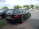 2003 Audi A6 - A black Audi A6 Avant wagon is parked on a brick surface, with another car to its left and buildings in the background.