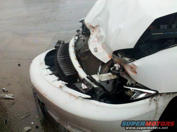 White SUV front end severely damaged after a collision. Water on the road
