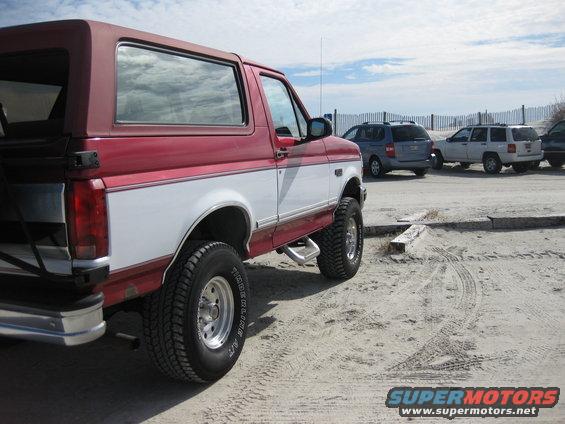 red and white SUV parked on sand, other SUVs in background