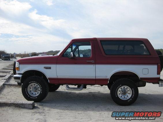 Side view of red and white 1995 Ford Bronco SUV with "BRONCO" badge visible
