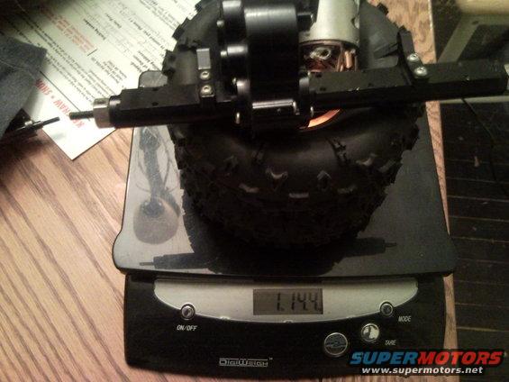 RC car suspension part and tire on a digital scale showing 1.144