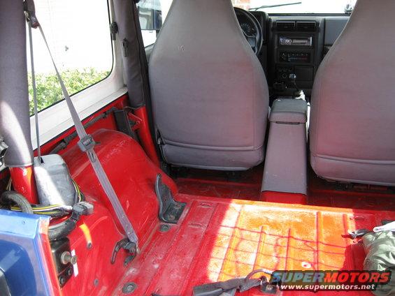 Jeep interior with red floor, grey seats, and dashboard visible. A Supermotors logo is in the lower right