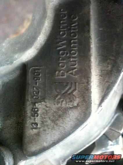 Close-up of a metal automotive part showing 'BorgWarner Automotive' and casting numbers '13-56-027-901'