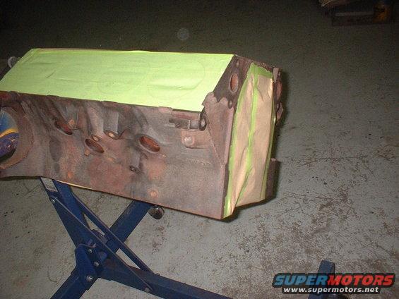 Engine block on a blue engine stand, partially covered with green masking tape