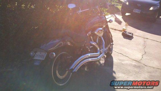 Motorcycle parked on a driveway with a car in the background
