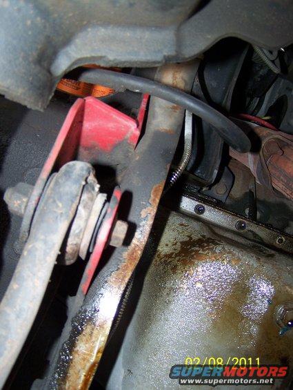 Undercarriage view of 1995 Ford Bronco showing red suspension component and oil pan