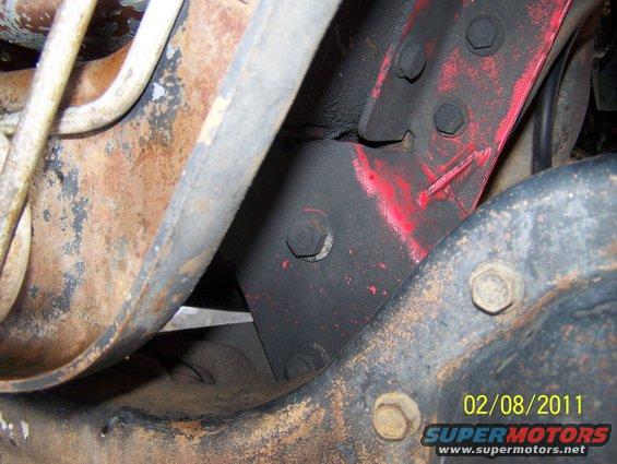 close-up of rusty vehicle frame with red painted bracket and bolts, date stamp 02/08/2011