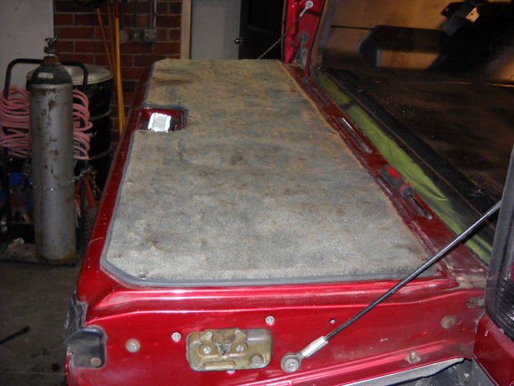 Red pickup truck tailgate interior with gray carpet and latch mechanism