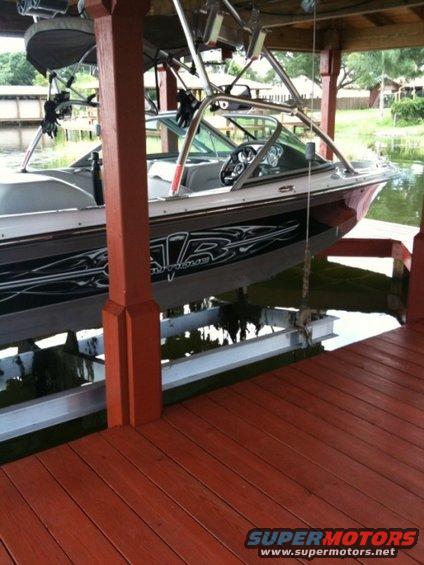 Boat with black and silver graphics on its side, docked under a covered structure