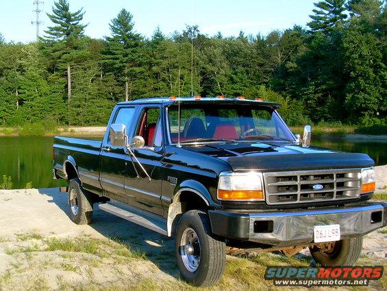 Black 1997 Ford F-350 parked by a lake with trees in the background