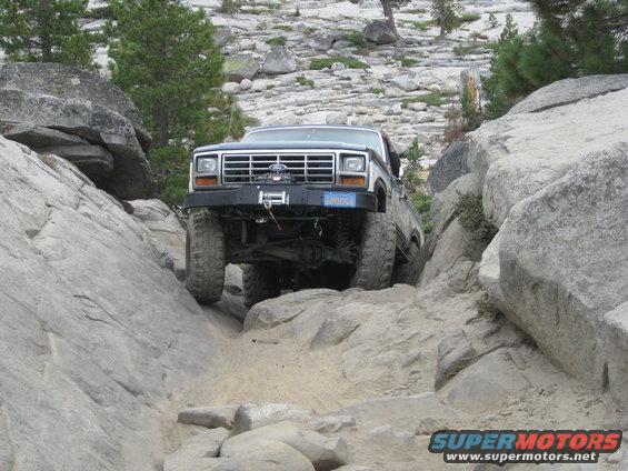 Dark blue Ford Bronco with a winch on the front bumper navigating a rocky, off-road trail