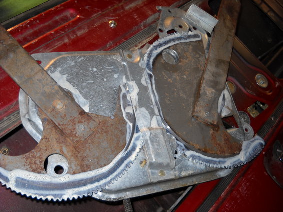 Close-up of a rusty metal window regulator mechanism with a toothed track