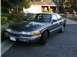 1992 Mercury Grand Marquis - A 1992 Mercury Grand Marquis sedan is parked in front of a house, with a second vehicle partially visible behind it.