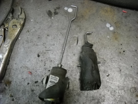 Two door lock actuators on a metal surface. One has a Ford Electro Systems label