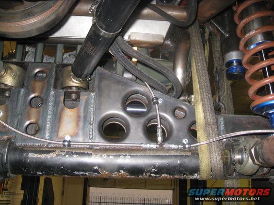 Close-up of custom suspension parts, including a shock absorber, metal brackets, and brake lines