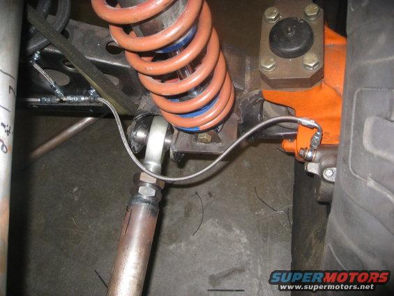 Close-up of suspension with orange coil spring and metal linkage