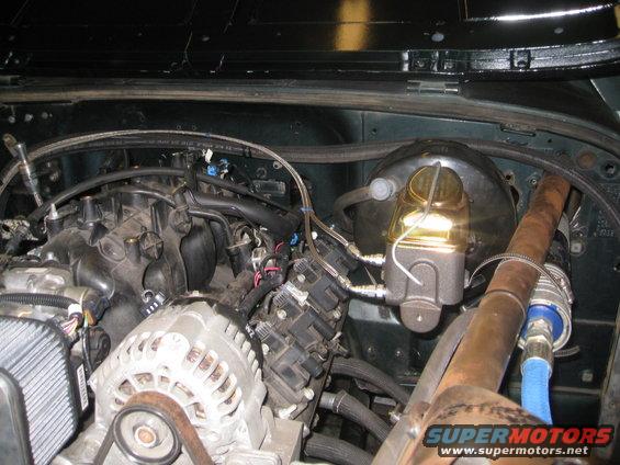 Engine bay showing a V8 engine, alternator, brake booster, and exhaust manifold