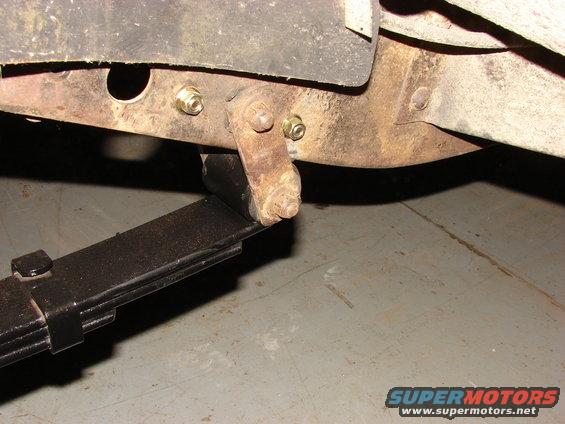 Close-up of a vehicle's leaf spring and frame mount with rusty bolts