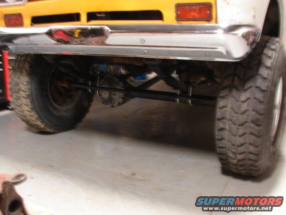 Yellow school bus chassis with chrome bumper and large tires, viewed from rear