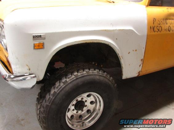 1971 International pickup truck fender with '100' badge, orange marker light, and large tire. Yellow and white paint scheme
