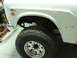 1971 International School Bus - Detail of a white International 100 pickup truck, showing the front wheel well and fender.