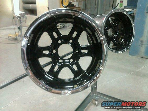 Two black Weld wheels with chrome lips and lug nut holes are mounted on a stand