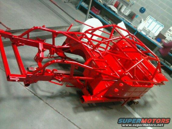 Red painted chassis frame with roll cage structure, possibly for a race car
