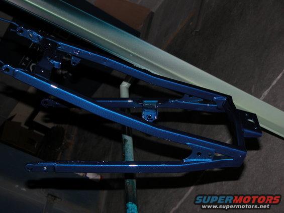 Blue metallic painted suspension part, angled view, on a stand