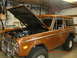 1973 Ford Bronco - The 1973 Ford Bronco is shown with its hood raised, revealing the engine compartment within a garage setting.