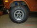 1973 Ford Bronco - The front wheel and fender of a 1973 Ford Bronco are shown, with aftermarket shocks and tires.