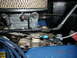 1973 Ford Bronco - Close-up view of a Weber carburetor and associated engine components, including throttle linkage and air filter.