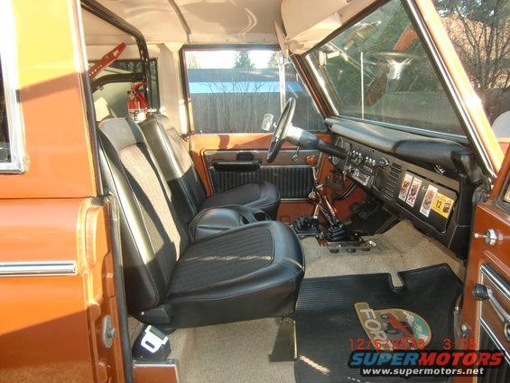 Interior of a 1973 Ford Bronco showing front seats, dashboard, and floor mats