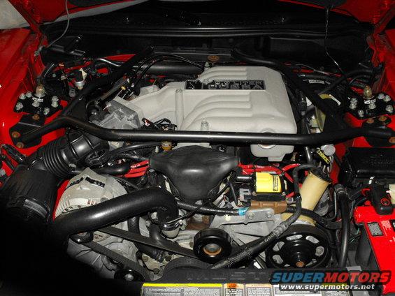 Red engine bay with a silver intake manifold and black hoses