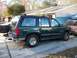 1994 Ford Explorer - A dark green 1994 Ford Explorer is parked in a driveway with other vehicles nearby.