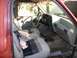 1994 Ford Explorer - The interior of a vehicle shows worn seats and a cluttered dashboard with a spray bottle on the passenger seat.