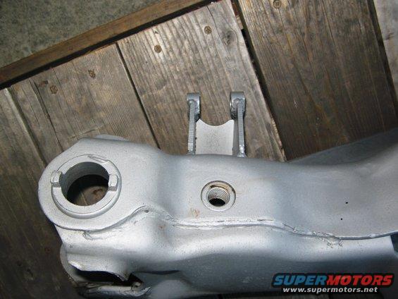 Close-up of a silver painted suspension beam part with mounting points