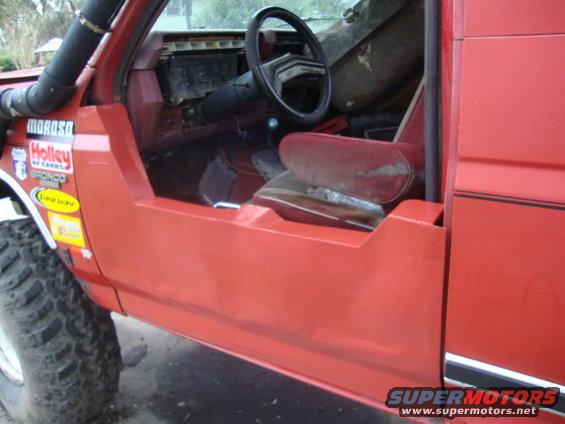 Red SUV interior with bucket seats, steering wheel, and door panel. Stickers on the fender include Holley and Moroso