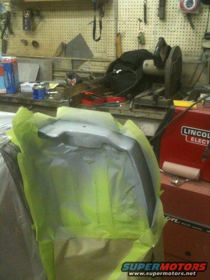 car part covered in masking tape and primer, ready for paint. Lincoln Electric welder in background