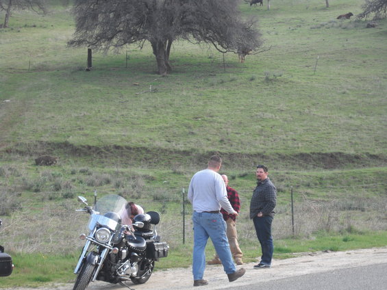 Motorcycle parked on dirt road with people standing nearby
