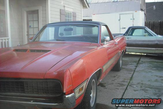 Red 1970 Ford Ranchero with a black vinyl top parked next to another vehicle