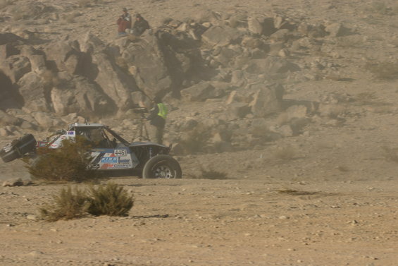 Off-road buggy with number 4450 on the side driving through a dusty desert landscape