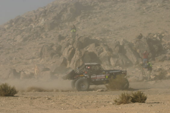 Off-road buggy in desert dust, side view. Some text visible on vehicle